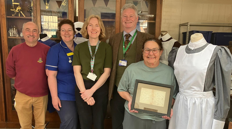 Colleagues and volunteers at the Creative Health and Heritage Centre, Glenfield Hospital. A framed letter from Florence Nightingale is held by Medical Equipment Project Officer, Sally Garner (on the right of the group)
