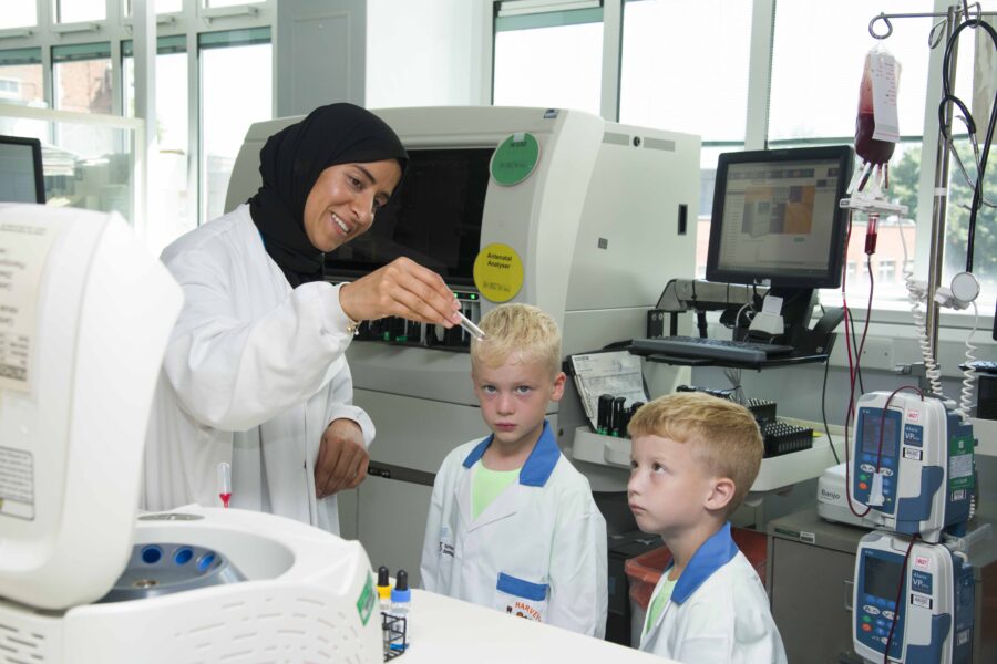 Shazia holding the test tube and showing it to Rocco and his brother