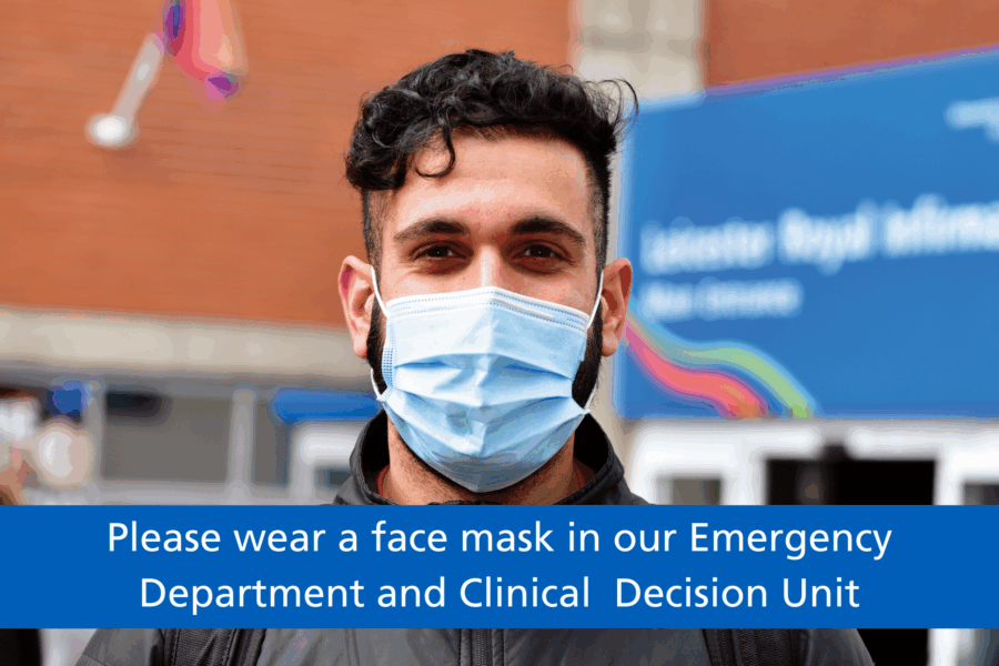 A man wearing a face mask, standing outside a hospital